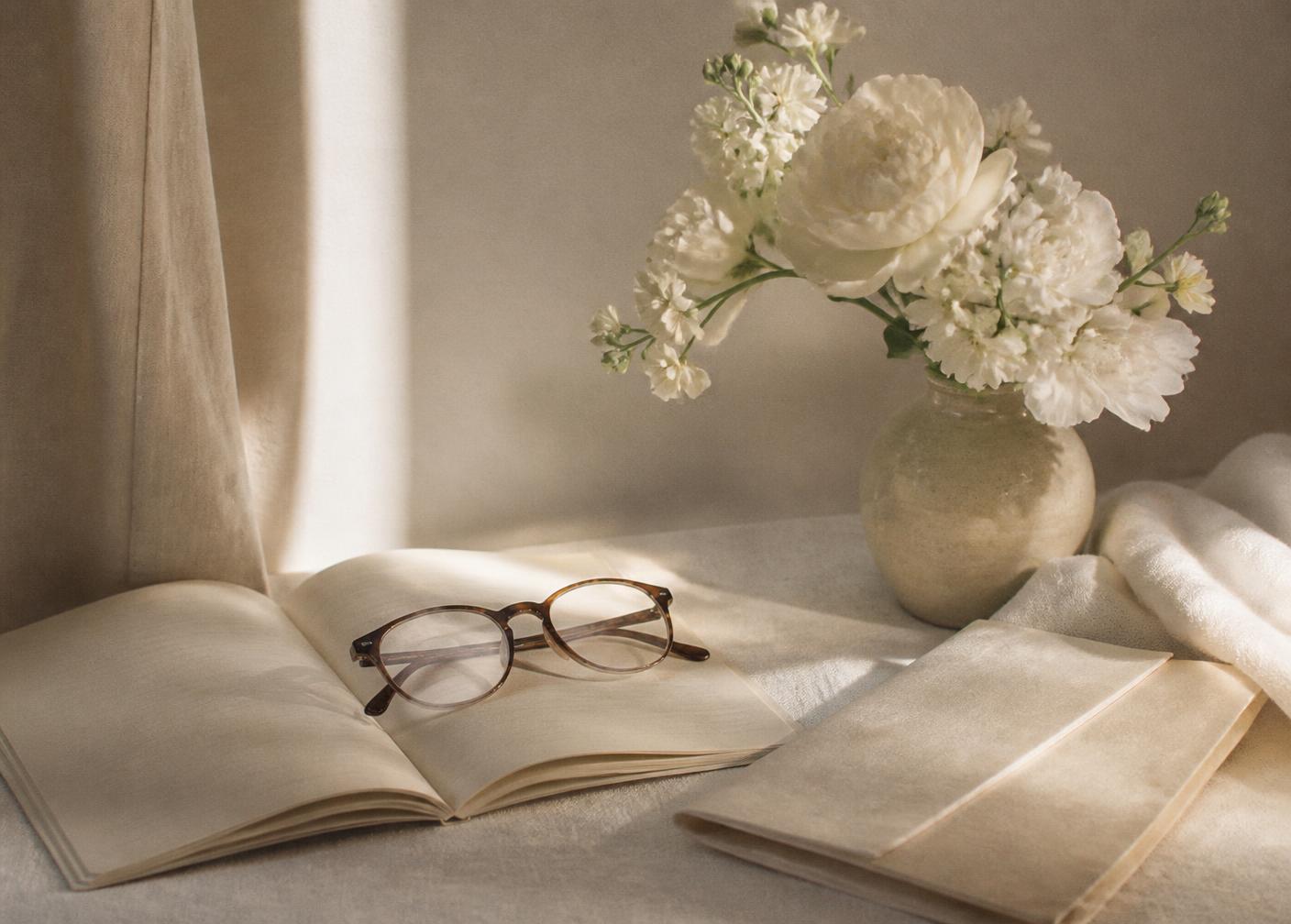 An open notebook and reading glasses in soft daylight